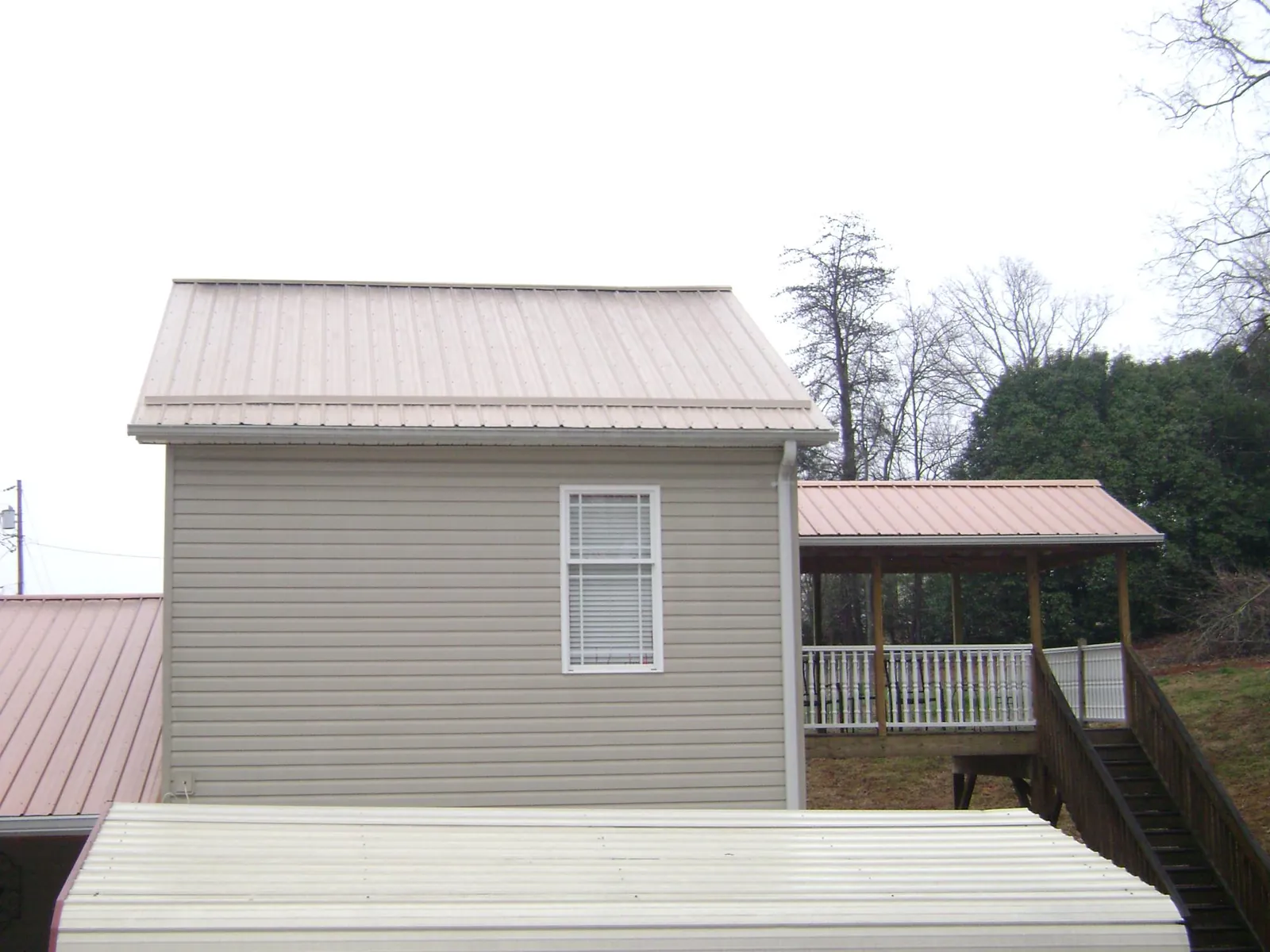 Tan metal roofs on a two story addition and attached porch, from a Roof Replacement job in Lewistown