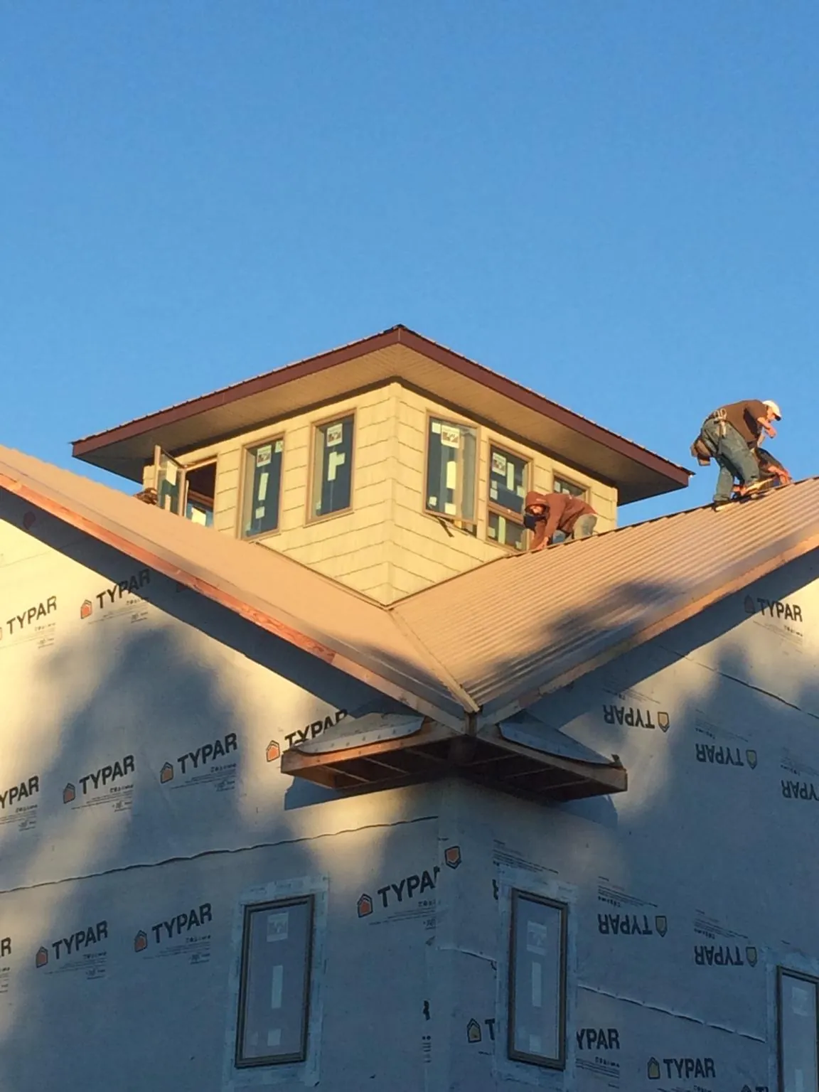 Roofers working around a rooftop cupola on a new metal roof at sunset — Roof Waterproofing in Lewistown by Roofing Brothers